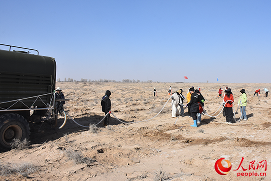 志愿者为新栽的树苗浇水。人民网 刘文邦摄